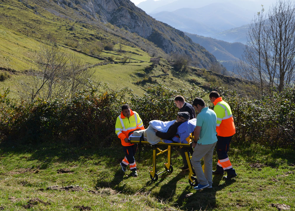 Voluntarios de la Ambulancia del Deseo atraviesan un monte empujando la camilla de un paciente.