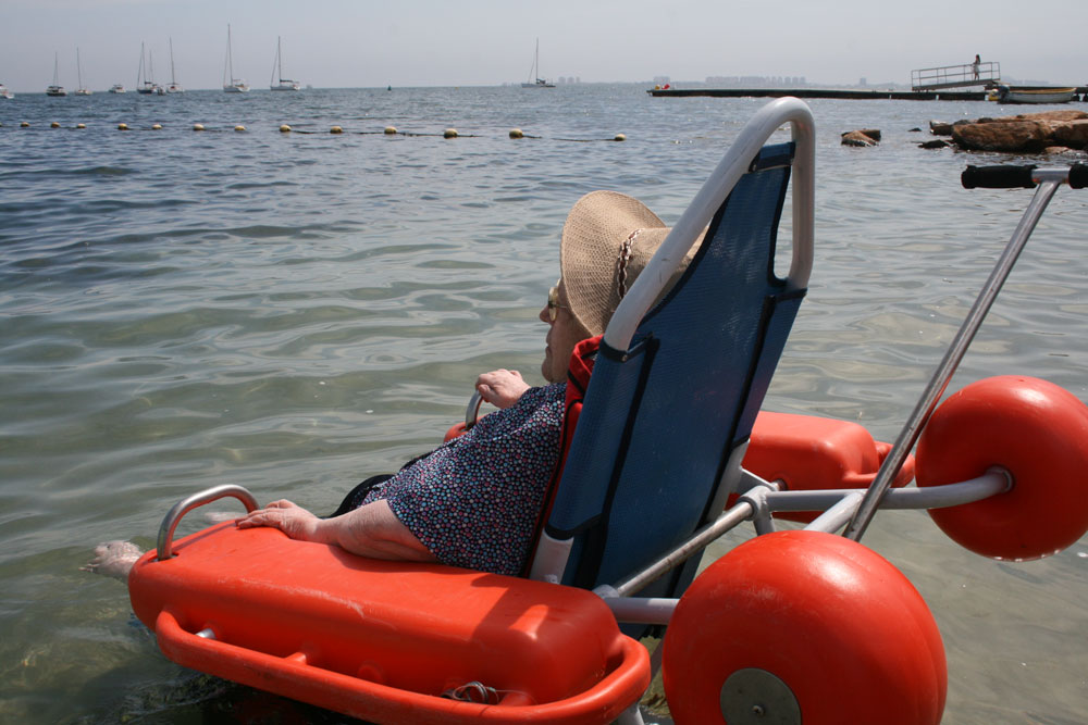 Imagen de un paciente, en una silla flotante, mirando al mar.